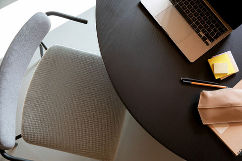 gray upholstered chair in front of a table with laptop