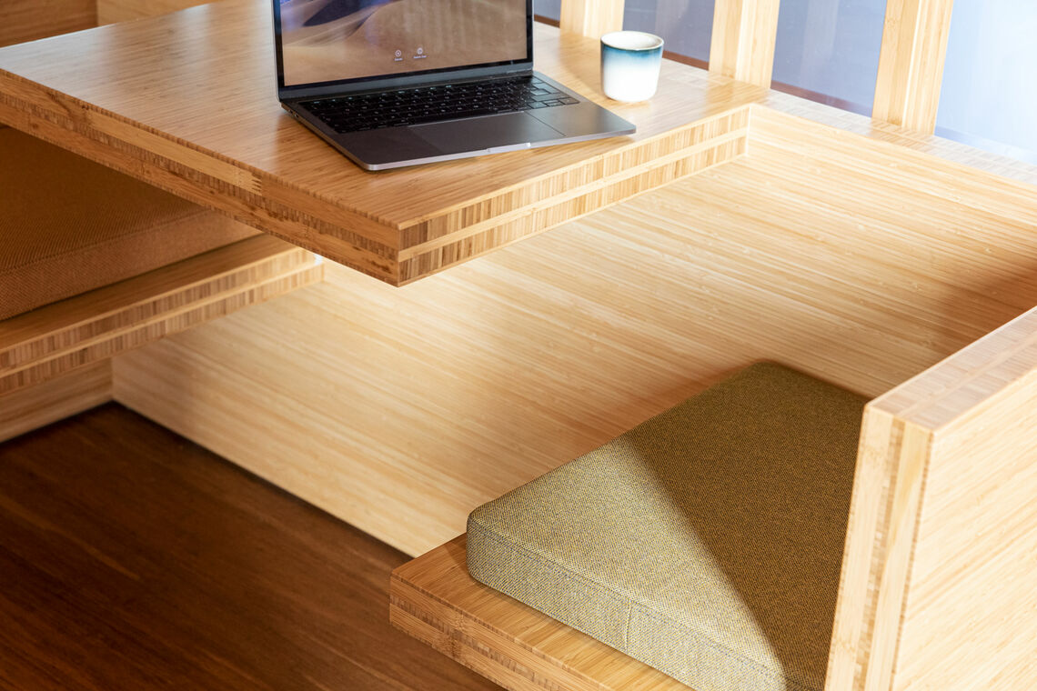 upholstered cushion on a wooden chair in front of a table with laptop