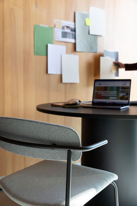 grey upholstered chair in front of a table with laptop